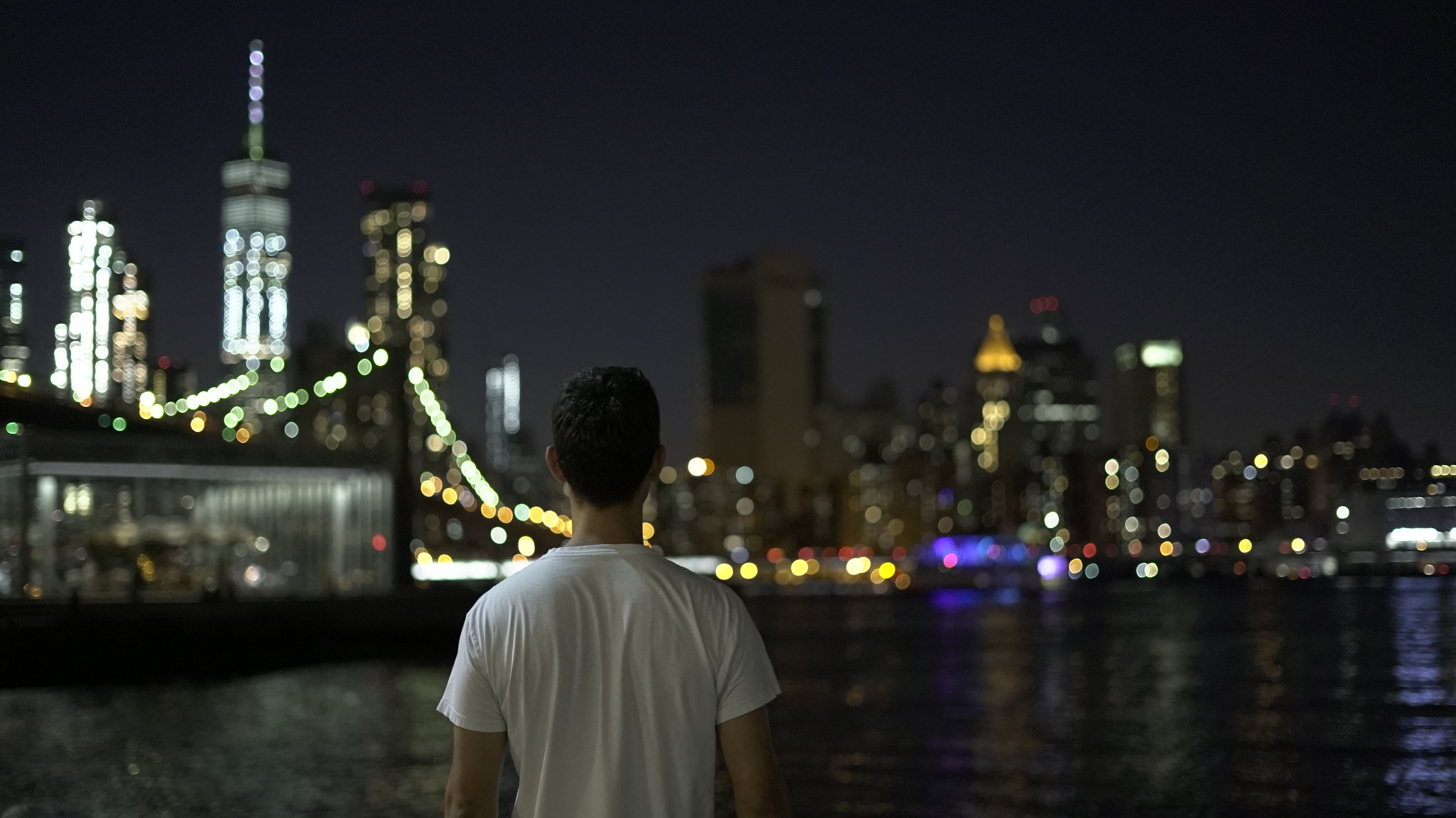 New York City at night, Fernando in middle, unfocused buildings skyline on the background